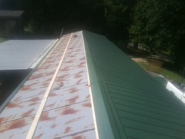 Old rusted panels beside newly installed green metal roofing — Wind Damage Roof Repair by Roofing Brothers in Fleming